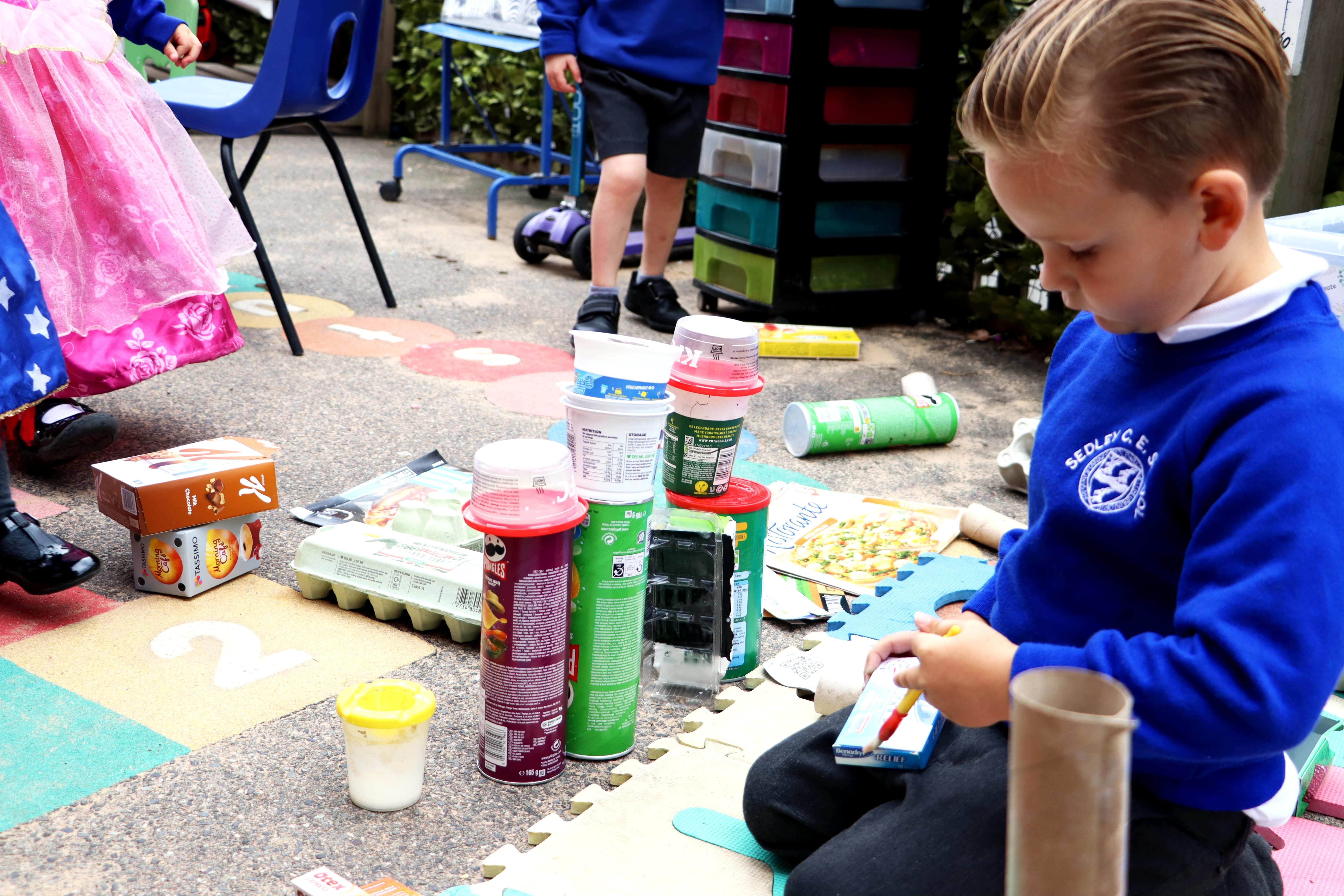 IMG_0224 EYFS pupil painting glue,and creating a tower with Pringles tubes and yoghurt pots
