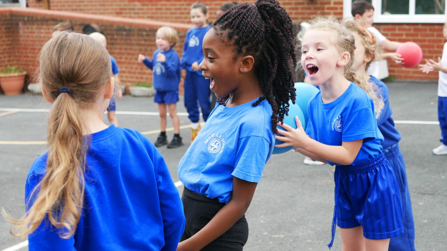 P1160663 (1) children laughing ouside on the playground during a PE lesson