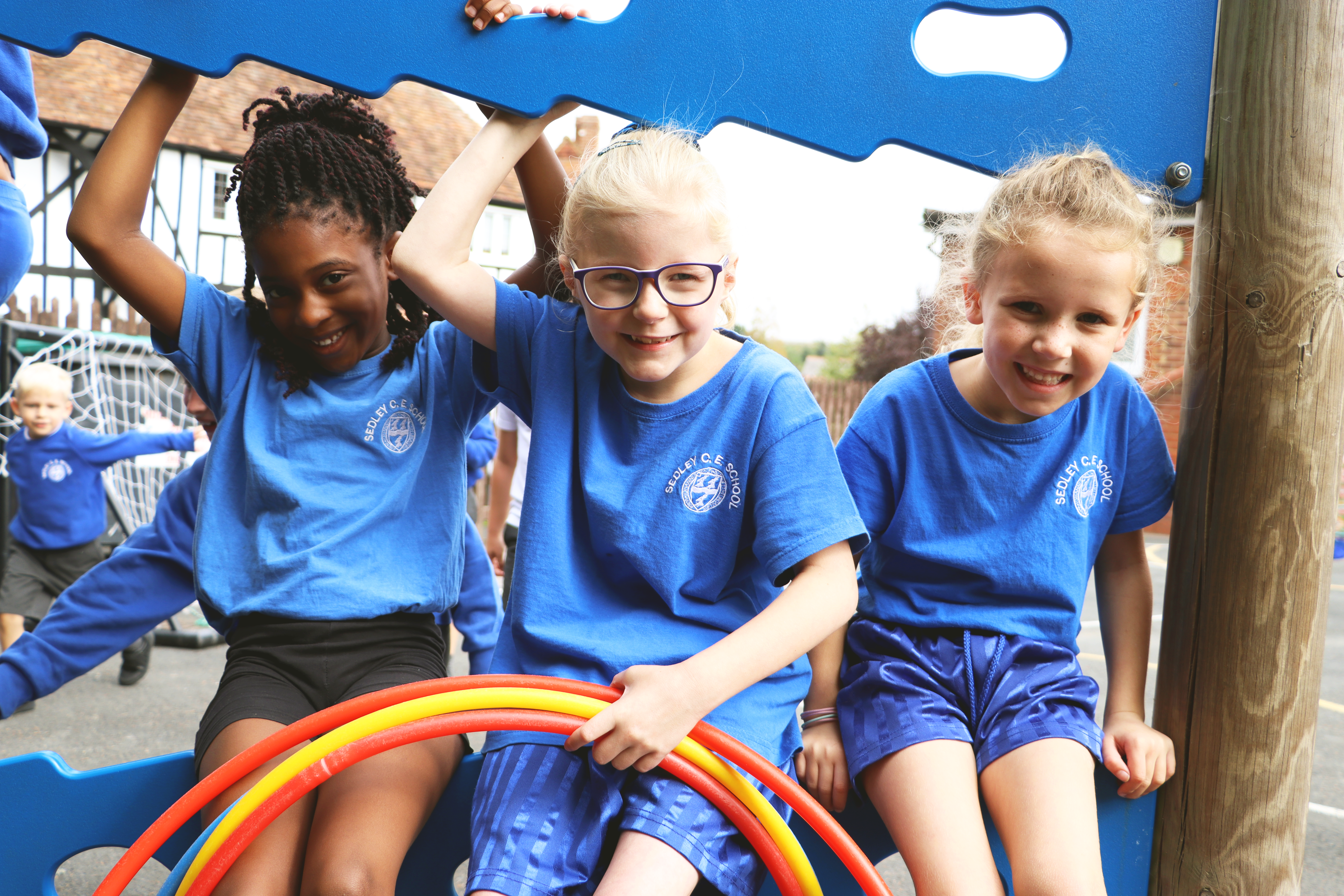 IMG_0317 three pupils smiling and sitting on the playground equipment at Sedleys primary school
