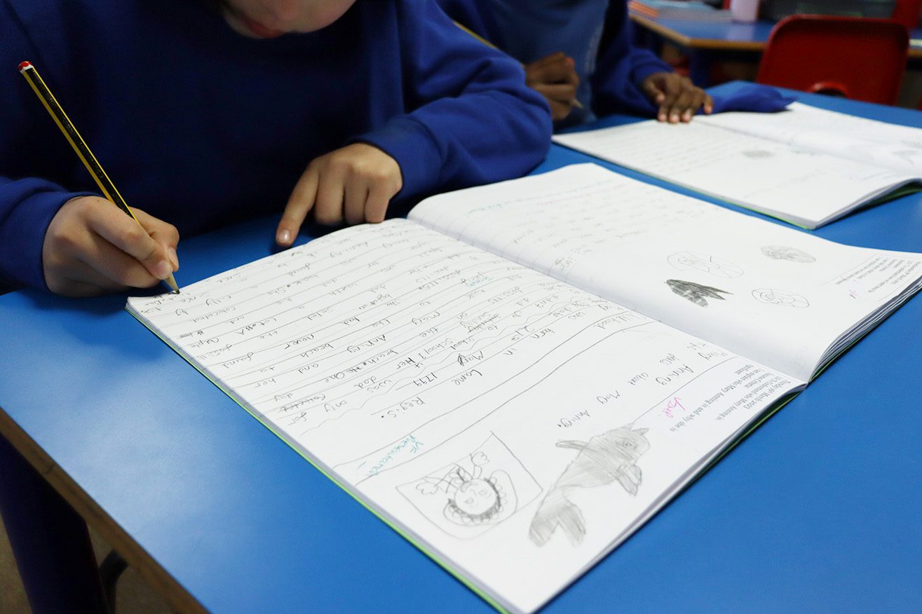 pupil writing in book