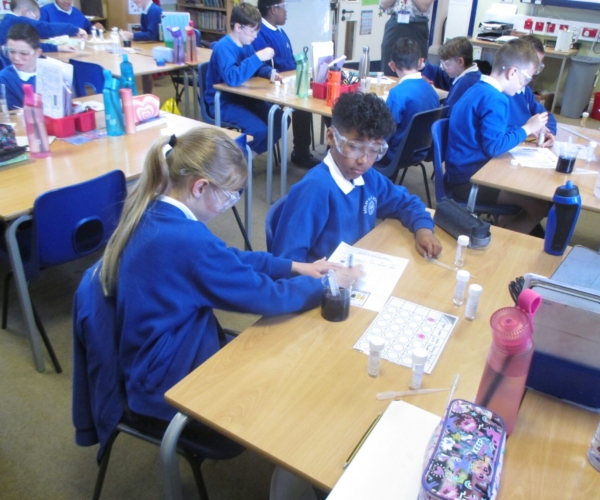 pupils at sedleys primary school with science google on, testing if a liquid is acidic or alkaline