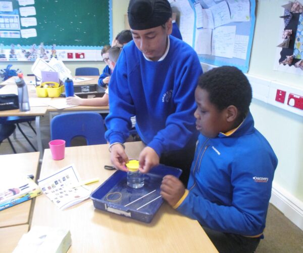 two sedleys pupils setting up a science experiment. placing a balloon over a beaker