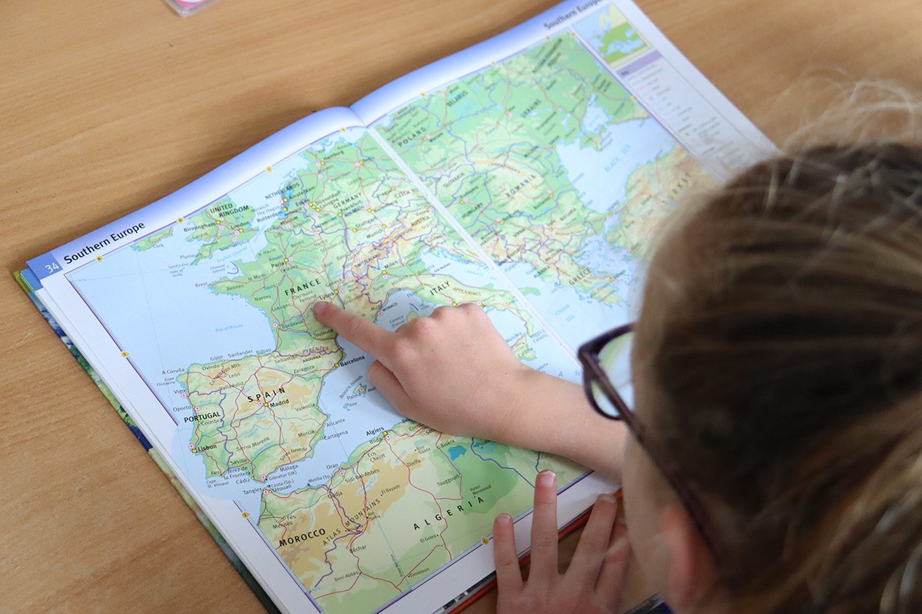 pupil pointing at france in atlas